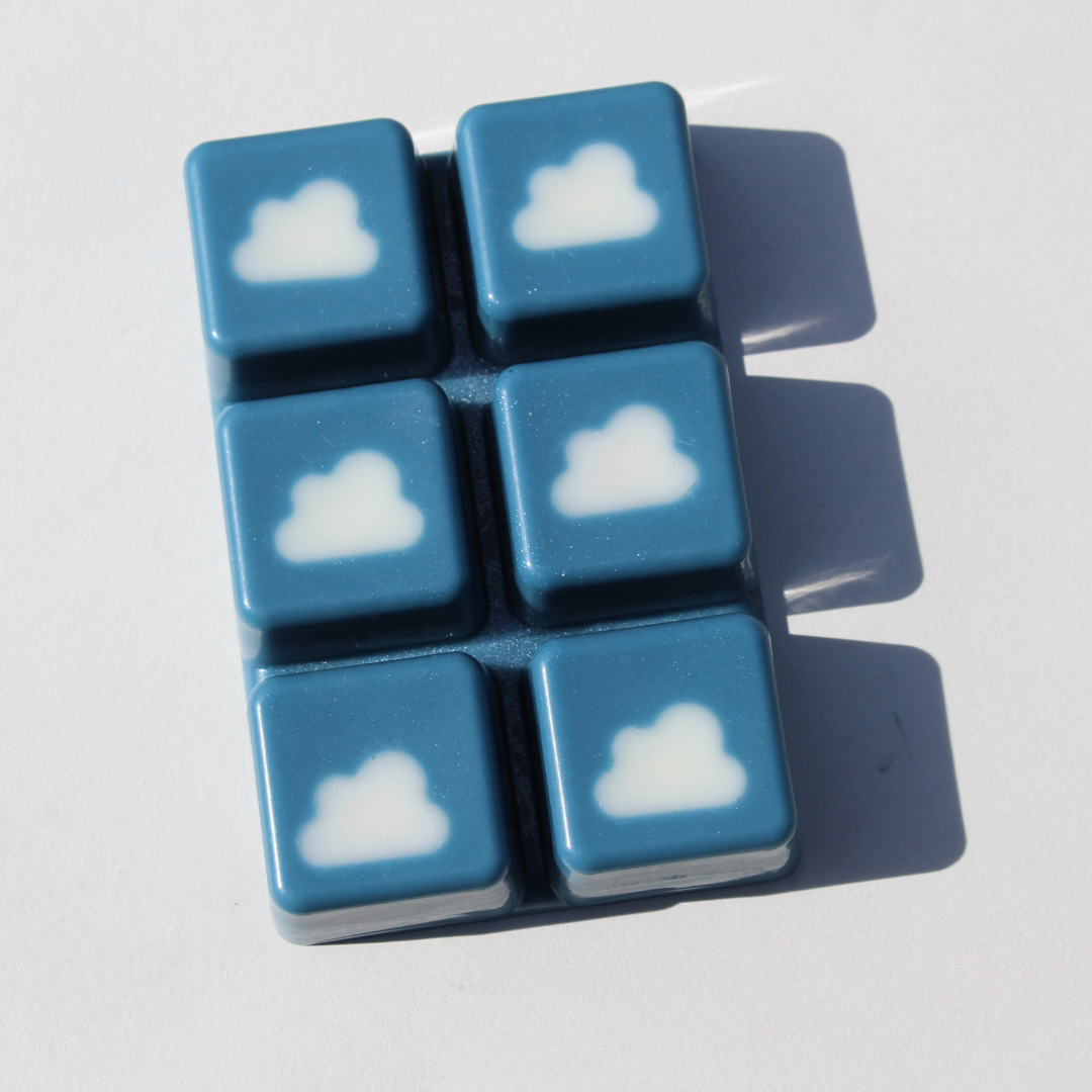 our breezy bunny wax melt out of the packaging it features white cloud embeds with a dark blue background you can see a slight shimmer to the soy wax