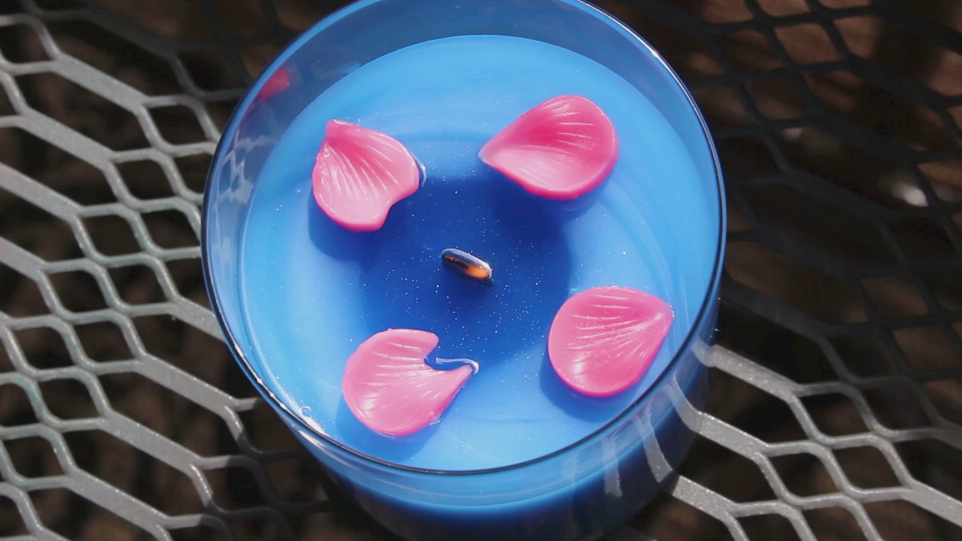 our sakura shiba candle sits in the sun the flower embeds slowly melt while the wooden wick crackles in the wax you can see small specks of glitter as the candle melts