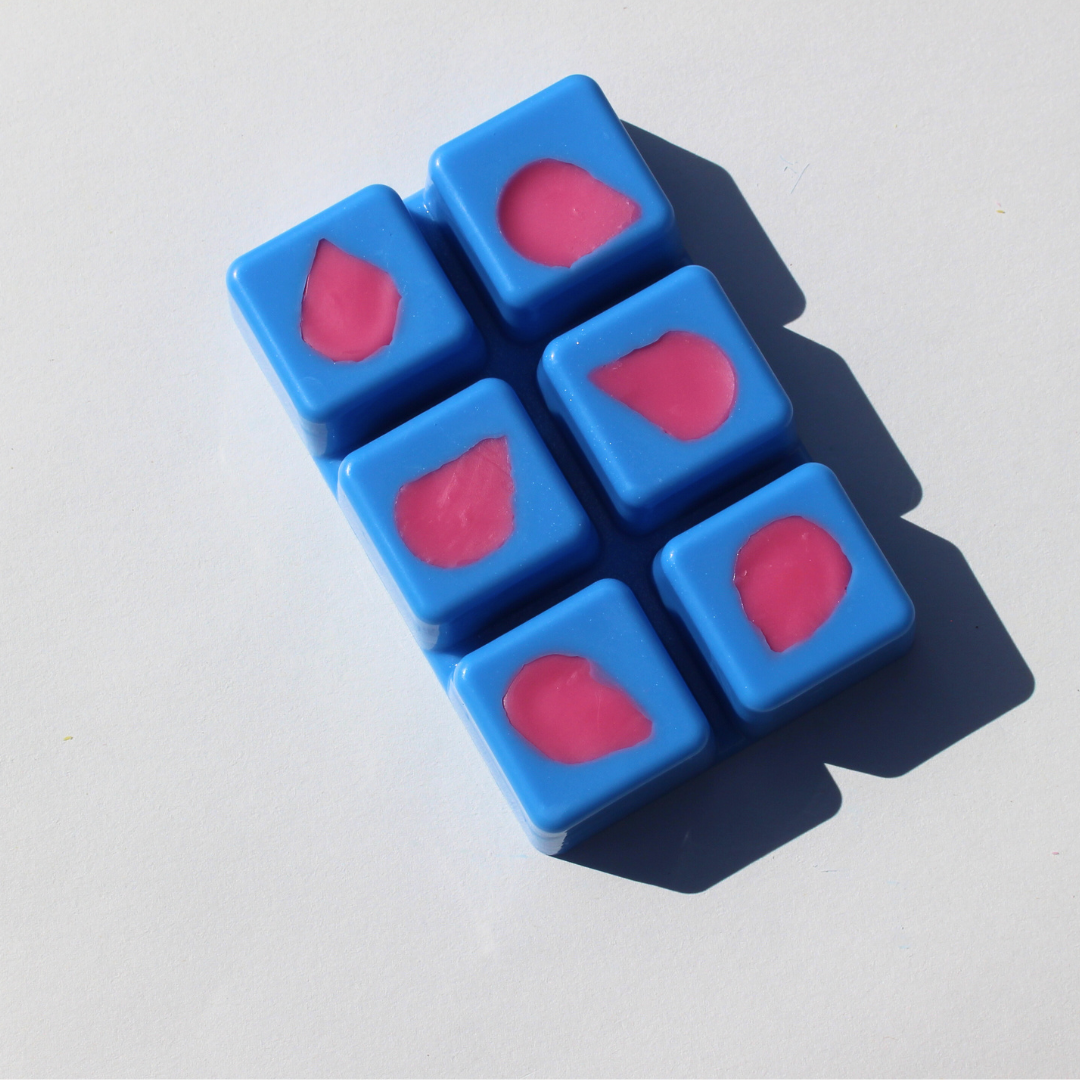 our sakura shiba wax melt out of the packaging features a light blue wax and light pink flower petals in each of the melts