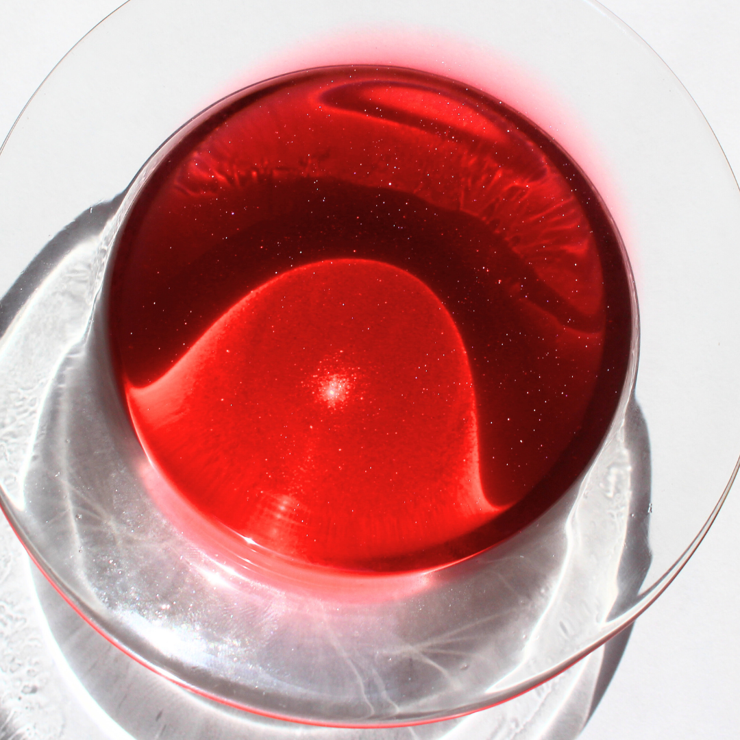 our cosmic candy wax melt fully melted it features a dark pink color where small sparkles can be seen in the wax 