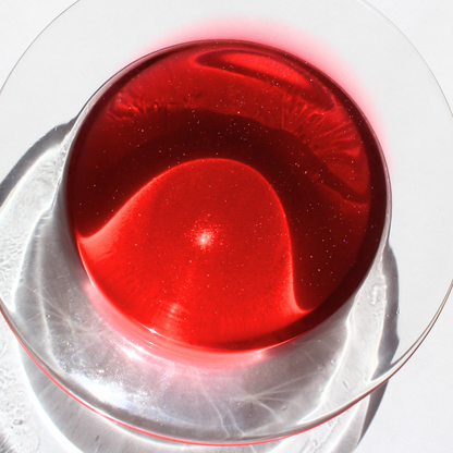 our cosmic candy wax melt fully melted it features a dark pink color where small sparkles can be seen in the wax 