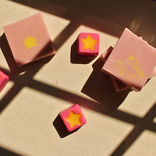our cosmic candy goat milk soap sits in the sun with yellow in the center of the soap and a pink background 5 oz soap