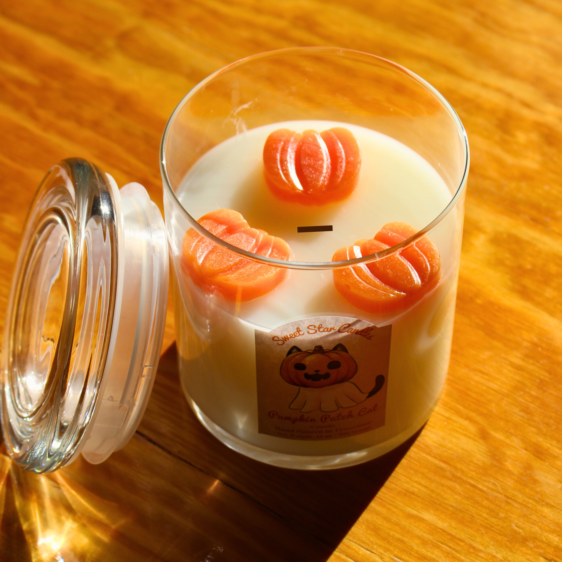 Candle with pumpkin design on a wooden surface