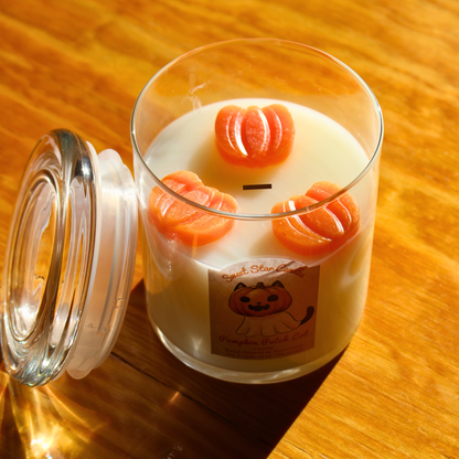 Candle with pumpkin design on a wooden surface