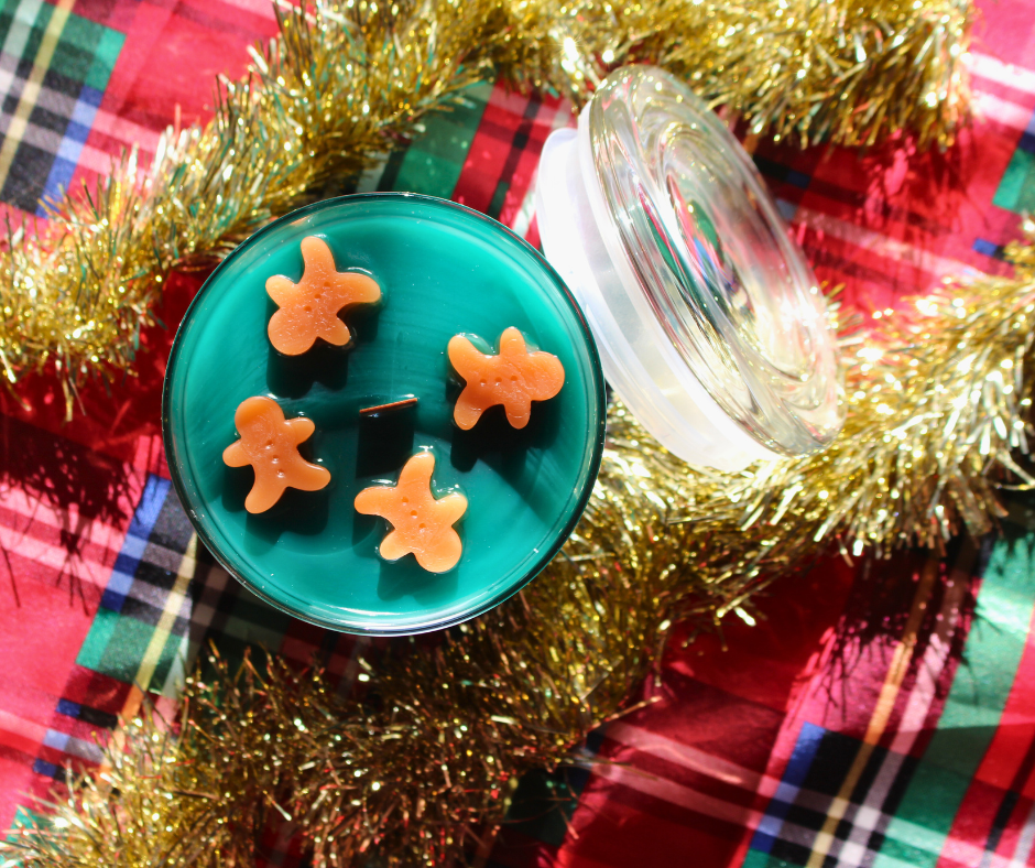 our reindeer cookies candle from the top you can see the Christmas green wax as well as 4 gingerbread cookie embeds surrounding a wooden wick with the glass lid leaned against the candle