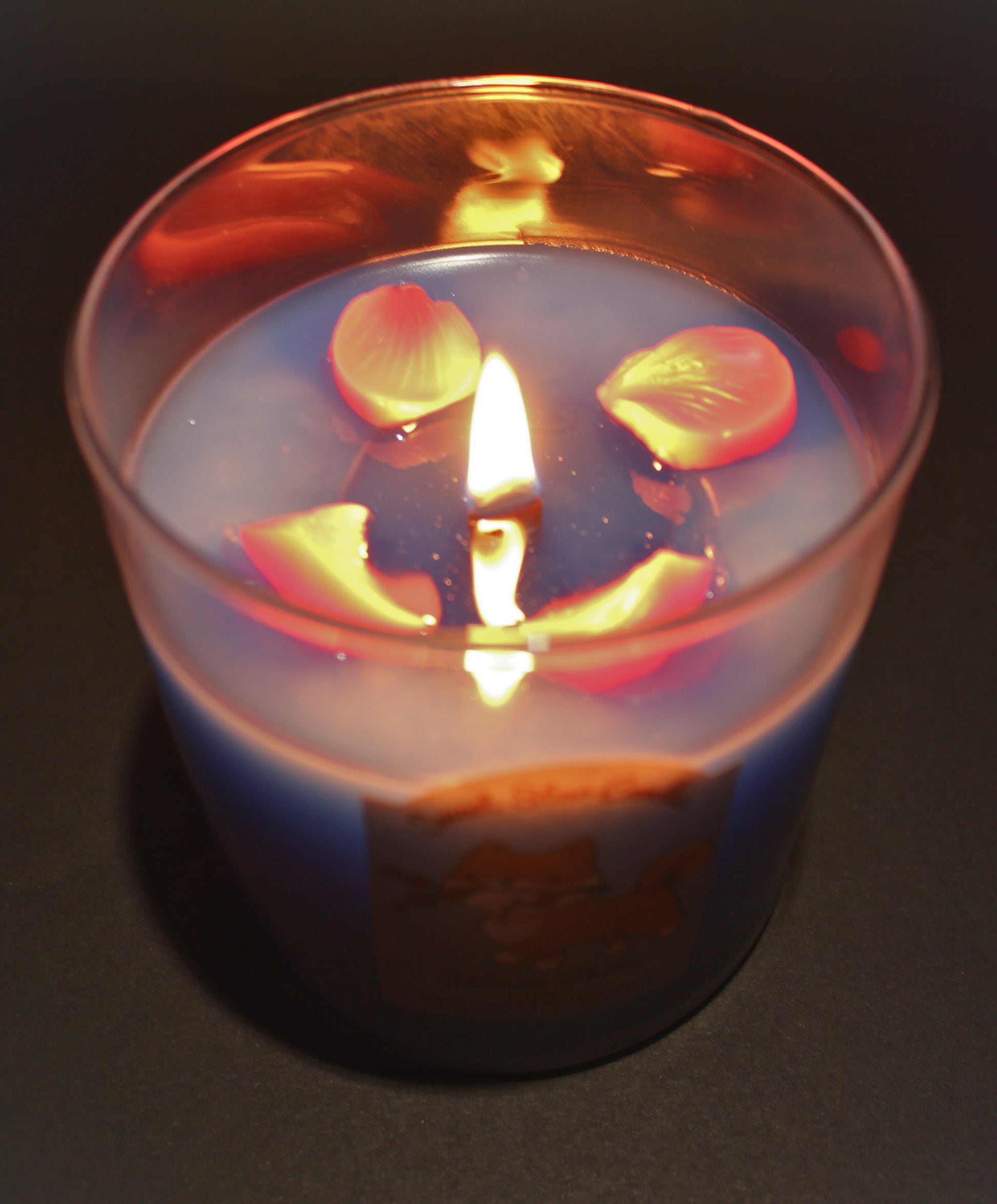 This shows the light blue wax melting around the wooden wick flame small sparkles can be seen as the wax and petals melt.