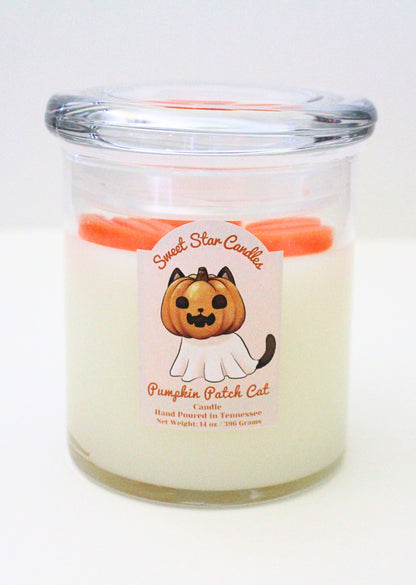 The candle feautures a white base with orange pumpkins on top of the wax with a glass lid the label features a black cat with a pumpkin on his head and a sheet ressembling a ghost covering the rest of his body his face also features a wide grin and his tail pokes out from beneath the sheet the label also reads sweet star candles pumpkin patch cat candle hand poured in tennessee with a net weight of 14 ounces