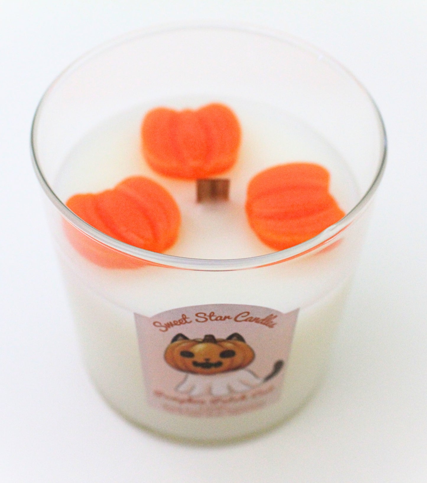 This image shows a better look of the bright orange pumpkins on top of the candle surrounding the wooden wick